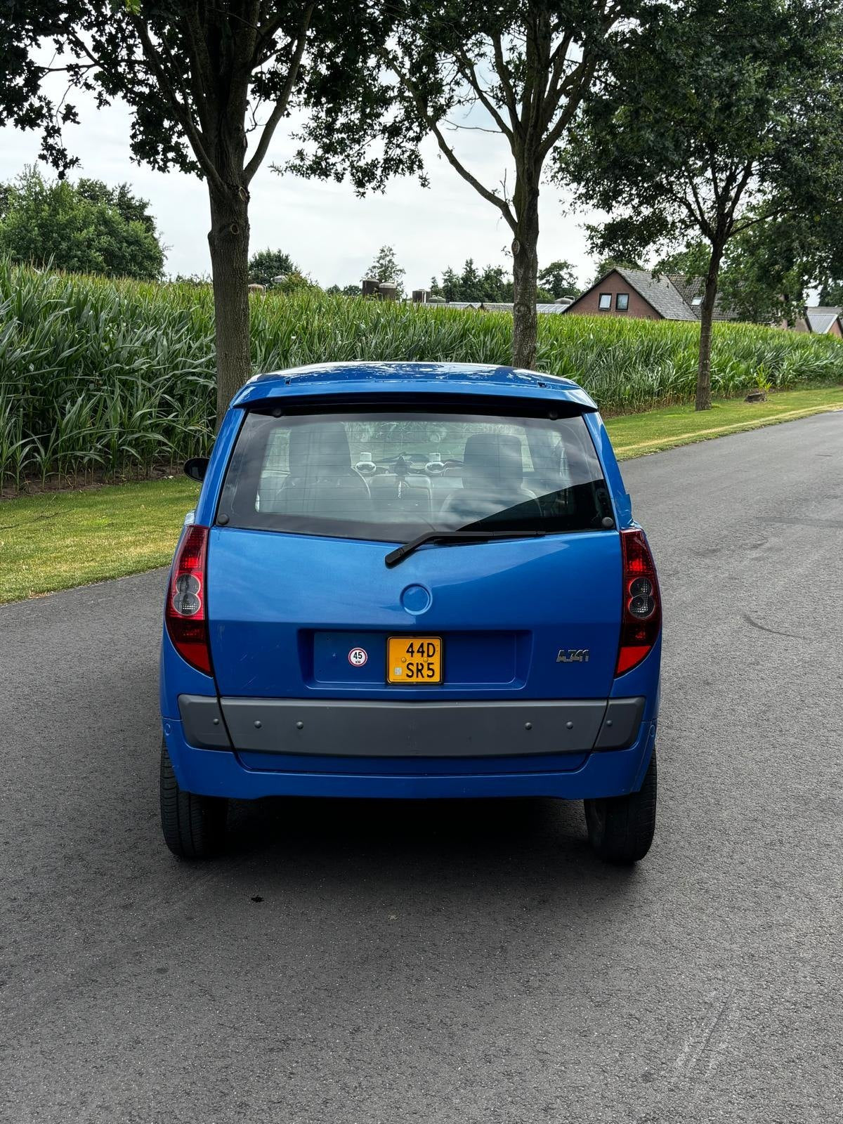 Recht van achteren, onder de bomen.
